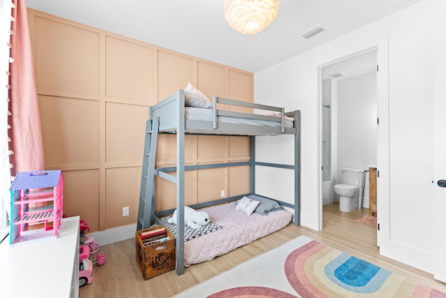 bedroom featuring connected bathroom and light hardwood / wood-style flooring