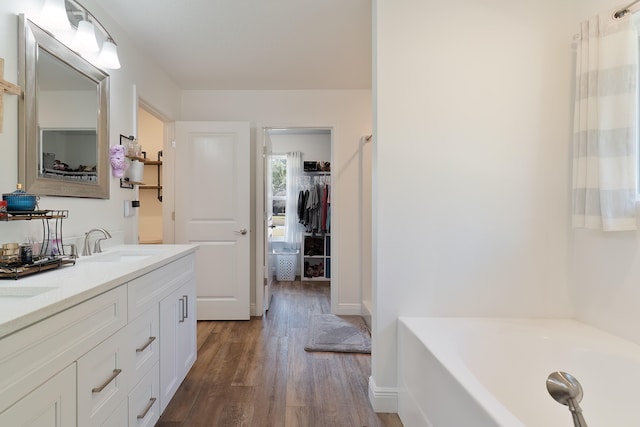 bathroom with hardwood / wood-style floors, vanity, and a bathing tub