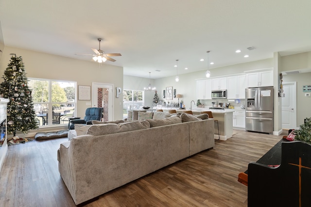 living room featuring sink, a healthy amount of sunlight, ceiling fan with notable chandelier, and hardwood / wood-style flooring