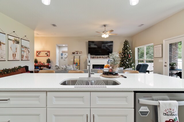 kitchen featuring white cabinetry, stainless steel dishwasher, ceiling fan, and sink