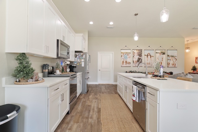 kitchen with appliances with stainless steel finishes, sink, decorative light fixtures, light hardwood / wood-style floors, and white cabinetry