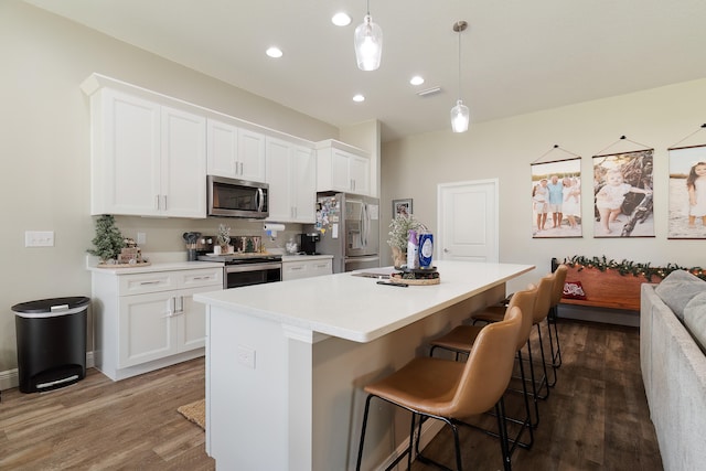 kitchen featuring pendant lighting, dark hardwood / wood-style floors, a kitchen island, and appliances with stainless steel finishes