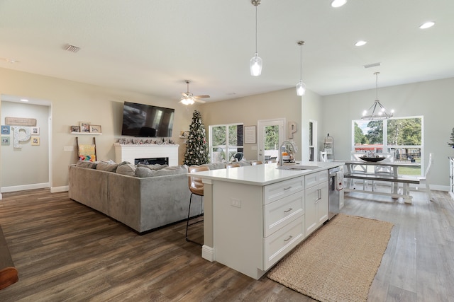 kitchen featuring sink, a center island with sink, dark hardwood / wood-style floors, white cabinetry, and hanging light fixtures