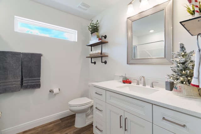 bathroom with hardwood / wood-style floors, vanity, toilet, and walk in shower