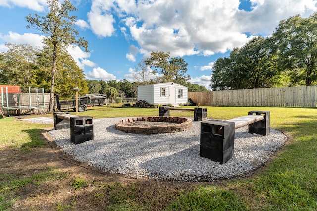 view of yard featuring a trampoline, a fire pit, and a storage unit