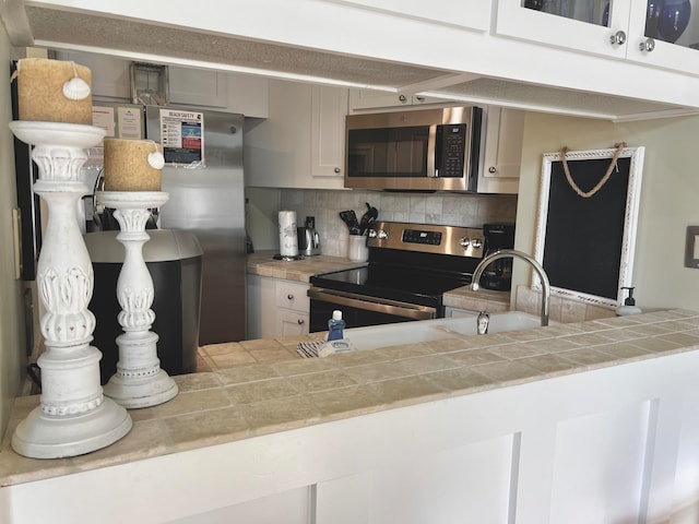 kitchen featuring backsplash, tile counters, sink, and stainless steel appliances