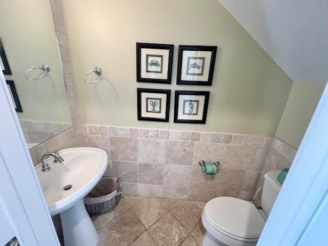 bathroom with toilet and tile walls