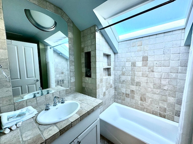 bathroom with vanity, tiled shower / bath combo, and vaulted ceiling