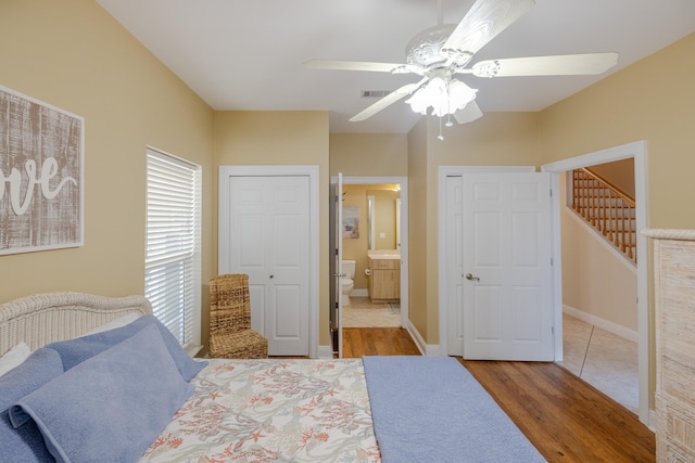 bedroom with hardwood / wood-style floors, ensuite bathroom, and ceiling fan