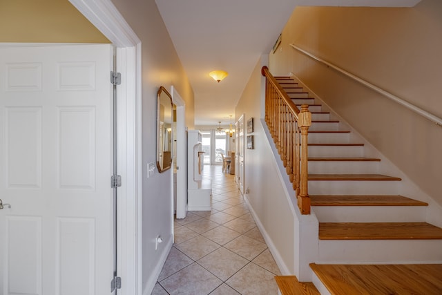 stairway with tile patterned floors and a notable chandelier