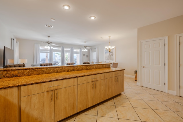 kitchen with light brown cabinetry, ceiling fan with notable chandelier, pendant lighting, and light tile patterned flooring