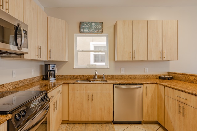 kitchen featuring stone counters, light brown cabinets, and stainless steel appliances