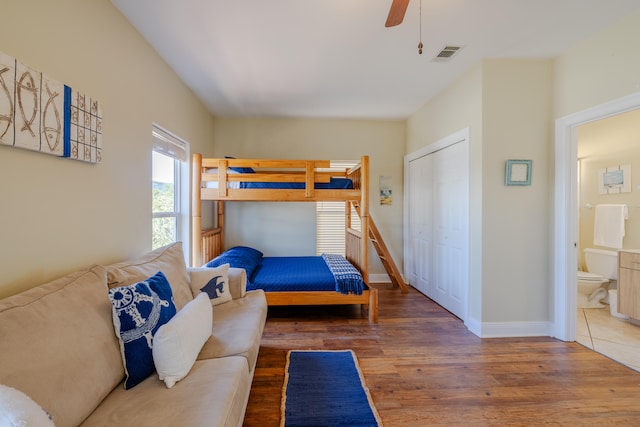 bedroom featuring connected bathroom, dark hardwood / wood-style flooring, ceiling fan, and a closet