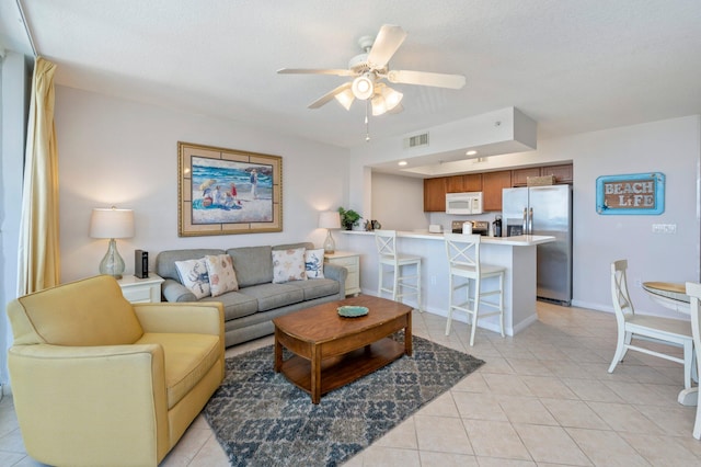 living room with ceiling fan, light tile patterned flooring, and a textured ceiling