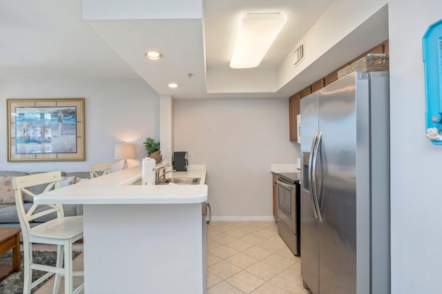 kitchen with sink, a kitchen breakfast bar, kitchen peninsula, light tile patterned floors, and appliances with stainless steel finishes