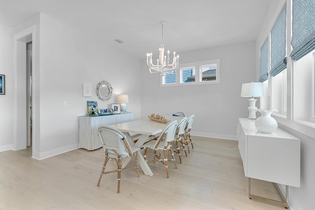 dining space with a notable chandelier and light hardwood / wood-style flooring