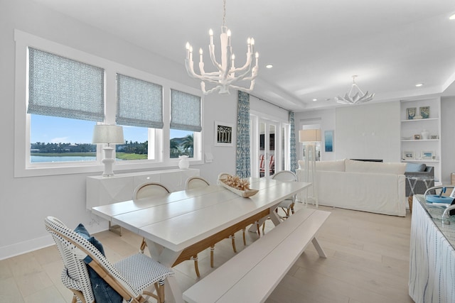 dining room with light wood-type flooring, a water view, and an inviting chandelier