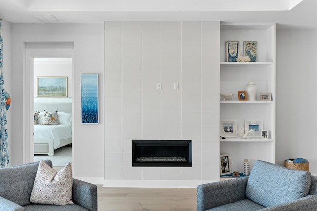 living room with a tiled fireplace and light hardwood / wood-style flooring