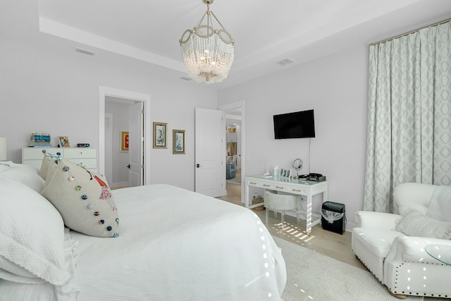 bedroom featuring light hardwood / wood-style floors, a tray ceiling, and a notable chandelier