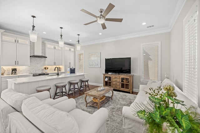 living room featuring crown molding, a wealth of natural light, sink, and wood-type flooring