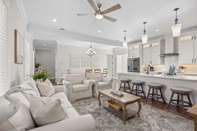 living room with hardwood / wood-style flooring, ceiling fan with notable chandelier, ornamental molding, and sink