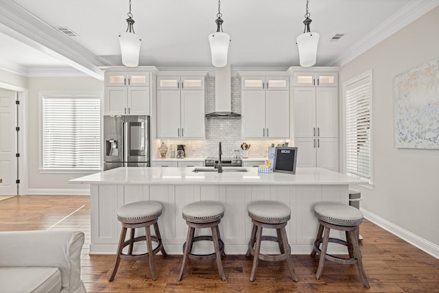 kitchen with pendant lighting, white cabinets, stainless steel fridge, an island with sink, and dark hardwood / wood-style flooring