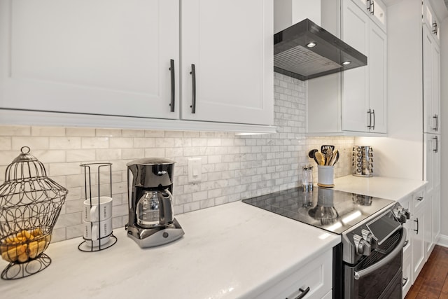 kitchen featuring stainless steel electric stove, white cabinets, wall chimney exhaust hood, and dark wood-type flooring