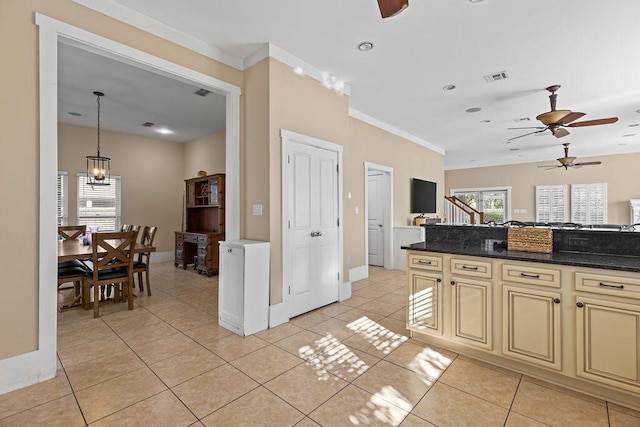 kitchen with crown molding, light tile patterned floors, hanging light fixtures, and cream cabinets