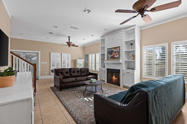 tiled living room with a fireplace, ceiling fan, and crown molding