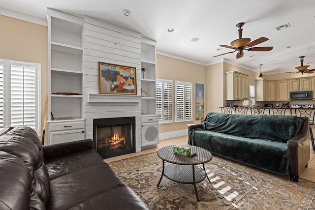 living room with light tile patterned floors, ornamental molding, ceiling fan, and a healthy amount of sunlight