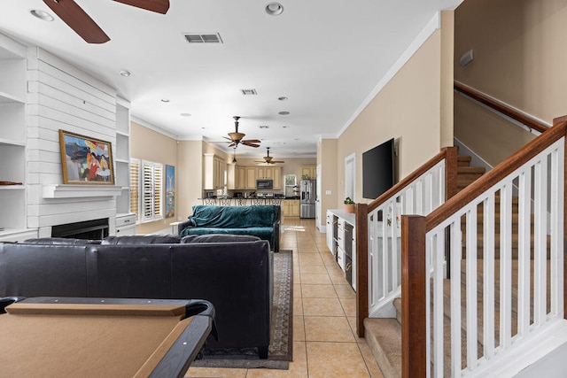 living room with a fireplace, a healthy amount of sunlight, light tile patterned flooring, and crown molding