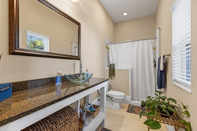 bathroom with tile patterned floors, walk in shower, vanity, and toilet