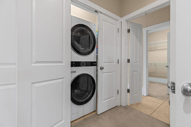 laundry room with light colored carpet and stacked washer and dryer