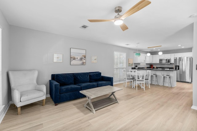 living room with ceiling fan and light hardwood / wood-style flooring