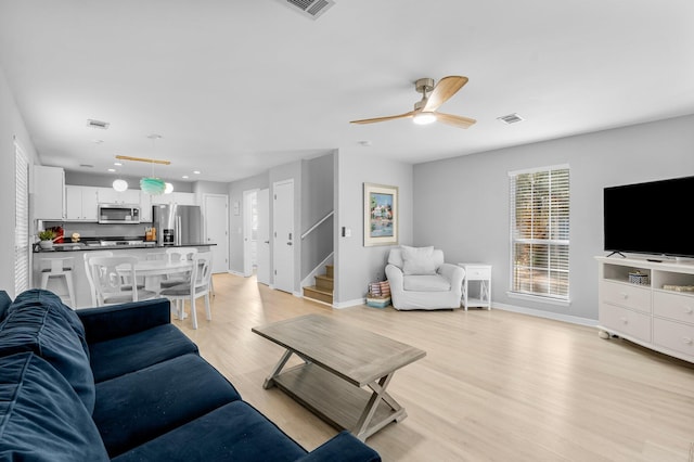 living room with light wood-type flooring and ceiling fan