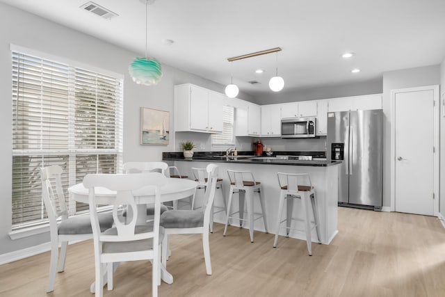 kitchen with sink, light hardwood / wood-style flooring, decorative light fixtures, white cabinetry, and stainless steel appliances