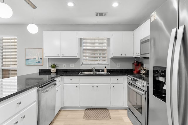 kitchen with light wood-type flooring, white cabinetry, sink, and appliances with stainless steel finishes