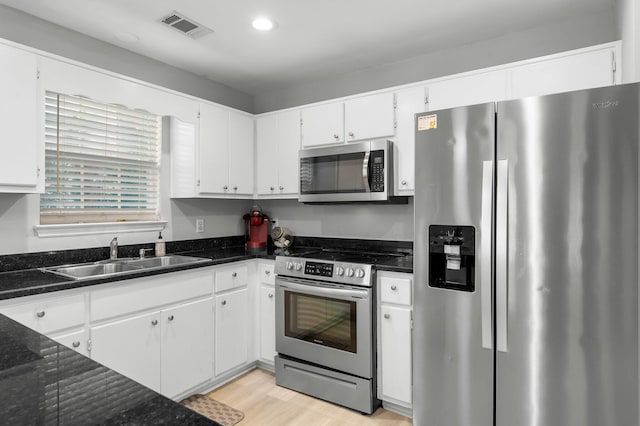 kitchen with sink, white cabinets, light hardwood / wood-style flooring, and appliances with stainless steel finishes