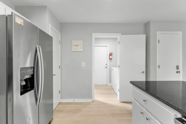 kitchen featuring white cabinetry, separate washer and dryer, stainless steel refrigerator with ice dispenser, dark stone countertops, and light wood-type flooring