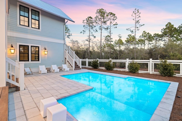 pool at dusk featuring a patio