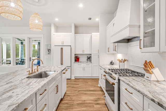 kitchen featuring custom range hood, white appliances, sink, white cabinets, and hanging light fixtures