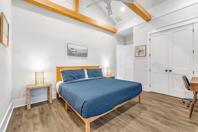 bedroom with ceiling fan, wooden ceiling, vaulted ceiling with beams, wood-type flooring, and a closet