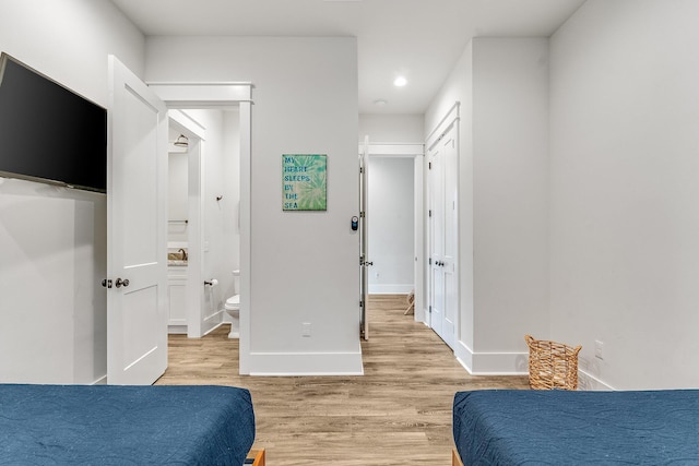 bedroom with light hardwood / wood-style floors and connected bathroom