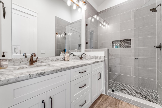 bathroom featuring vanity, a tile shower, and wood-type flooring