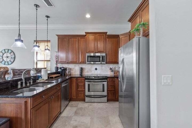 kitchen featuring sink, backsplash, dark stone counters, decorative light fixtures, and appliances with stainless steel finishes