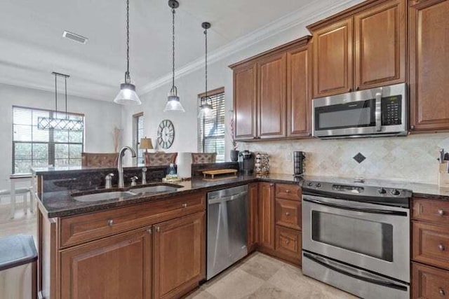 kitchen featuring sink, stainless steel appliances, dark stone countertops, decorative light fixtures, and ornamental molding