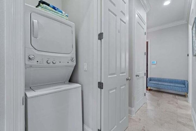 clothes washing area featuring ornamental molding and stacked washer / drying machine