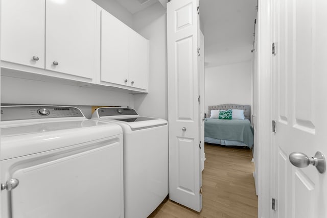 laundry area featuring cabinets, light wood-type flooring, and separate washer and dryer