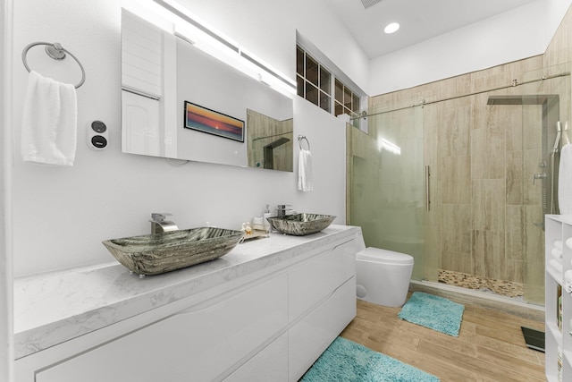 bathroom featuring vanity, hardwood / wood-style flooring, toilet, and a shower with door