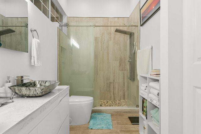 bathroom with hardwood / wood-style floors, vanity, toilet, and a shower with door